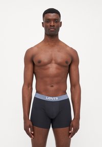 Crni bokserice s laganom plavom elastikom s Levi's logom, izrađene od glatkog, rastezljivog materijala, s uskim krojem i jednostavnim dizajnom.