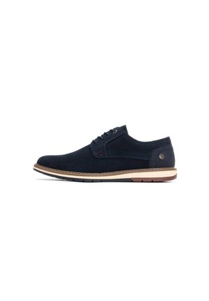 Zapato de ante azul marino con una suela intermedia de color marrón claro, diseño de cordones, puntera redonda y mínimas acentuaciones rojas cerca de los ojales y en el lateral.