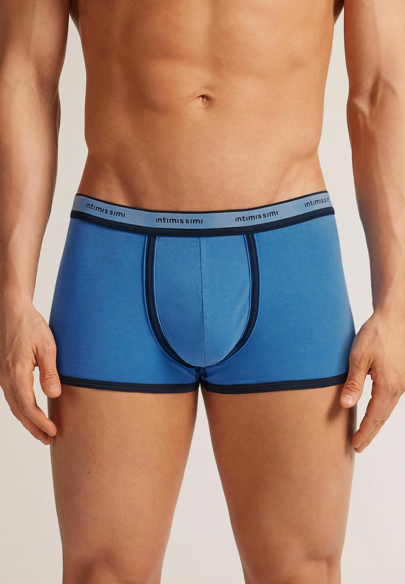 Blå bomullskalsonger med en tight passform, prydda med en kontrasterande mörk midja och detalj i frontfickan. Slät textur och minimal sömdesign.