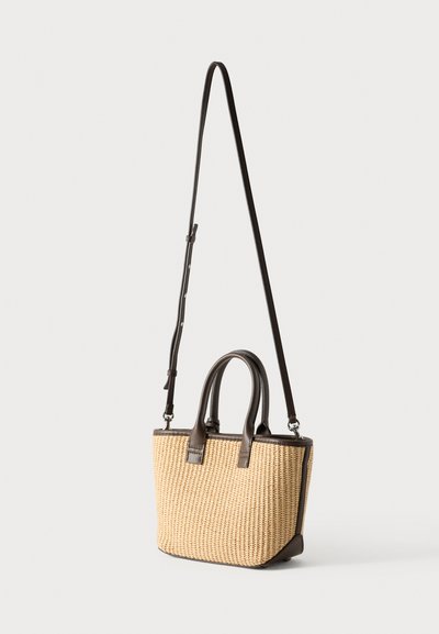 Πλεκτή τσάντα από ψάθα με σκούρες καφέ δερμάτινες λεπτομέρειες, διαθέτει δύο επάνω λαβές και αποσπώμενο ιμάντα ώμου. Ορθογώνιο σχήμα.