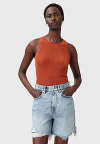 Rood-oranje geribbelde tanktop, gecombineerd met lichtblauwe high-waisted denim shorts met rafelige zomen en voorkwasten.