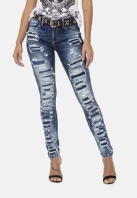 Versleten denim jeans met meerdere horizontale scheuren, donkerblauwe kleur, slim fit en gecombineerd met een zwarte gesp met studs.