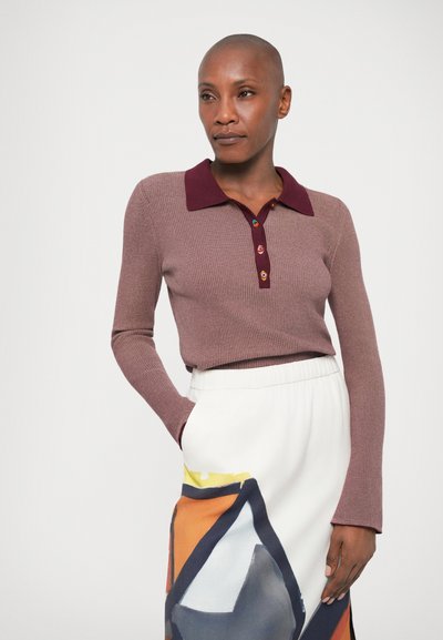 Hosszú ujjú bordázott pulóver mályva színben, bordó polo gallérral és színes gombokkal, fehér szoknyával párosítva, amely absztrakt geometriai mintákkal díszített.