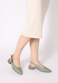 Groene leren slingback schoenen met een spitse neus, kleine blokhak en een strikaccent op de hielriem. Gladde textuur en eenvoudig ontwerp.