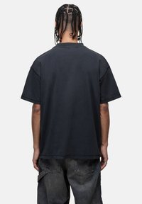 Zwarte katoenen T-shirt met korte mouwen, relaxte pasvorm en ribgebreide halslijn, gecombineerd met vervaagde spijkerbroeken. Eenvoudig ontwerp zonder zichtbare logo's.