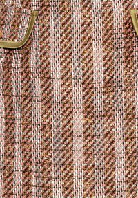 Woven fabric in pink, gold, and white with a textured pattern. Features two small pockets trimmed in a gold-colored material.