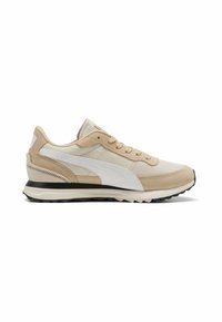Zapatilla deportiva beige con parte superior de malla, acentos de ante y suela de goma negra. Raya lateral blanca distintiva y detalles texturizados.