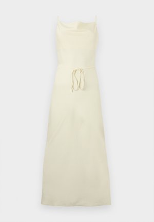 Μακριά αμάνικο φόρεμα εκρού με λεπτές τιράντες, ίσια λαιμόκοψη και ζώνη στη μέση σε μονόχρωμο φόντο.