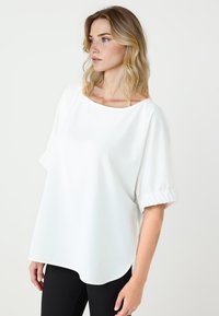 Witte, kortgemouwen blouse met een ronde hals en gathered mouwen. Dikke textuur, losse pasvorm en gebogen zoom.