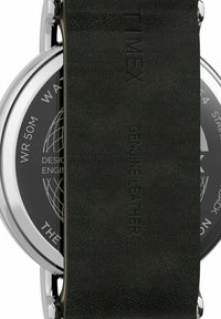 Ura Timex z črnim paščkom iz pravega usnja in srebrnim ohišjem iz nerjavečega jekla. Črni številčnik z vodoodpornostjo do 50 m.