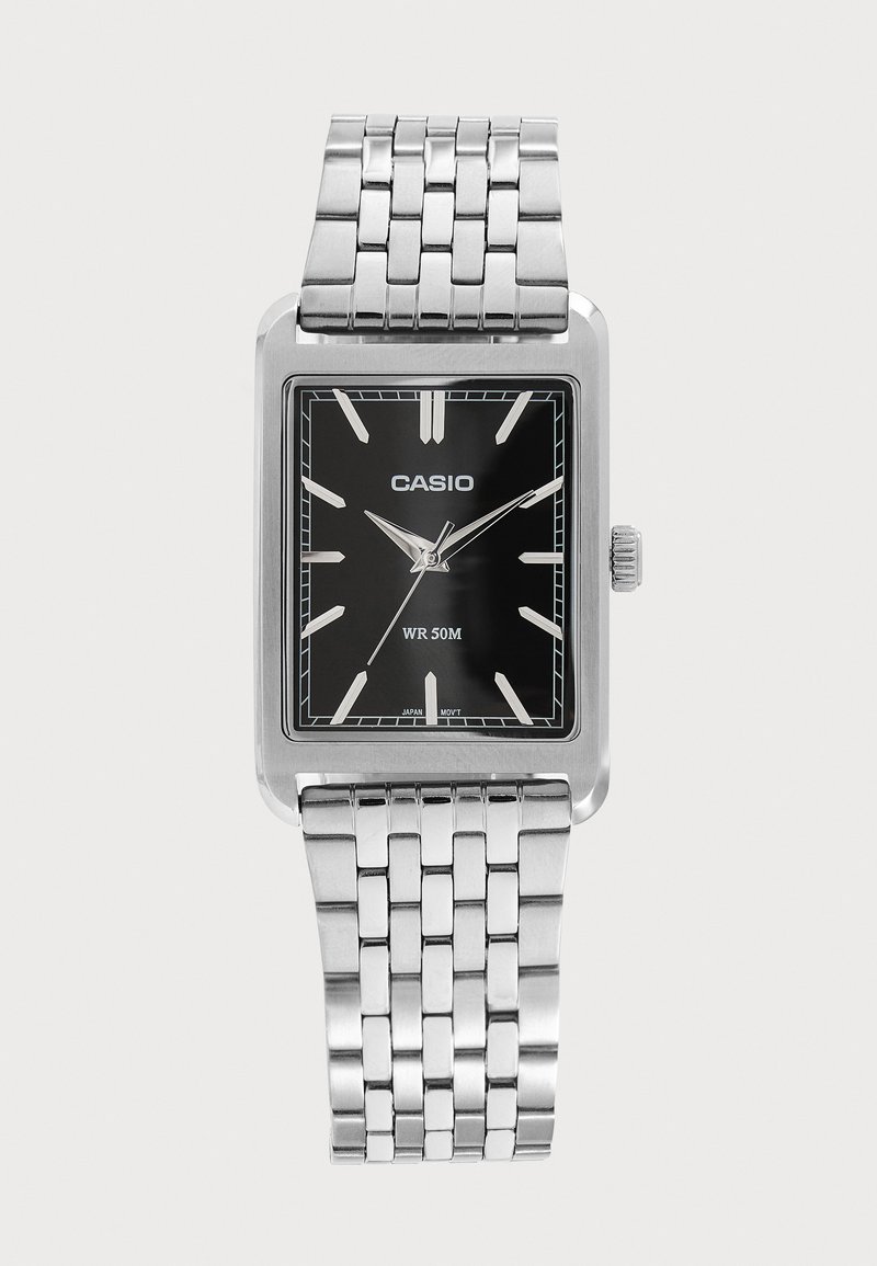 Montre-bracelet Casio argentée avec cadran noir rectangulaire, index et aiguilles argentés, bracelet à maillons en métal, étanche jusqu’à 50 mètres.