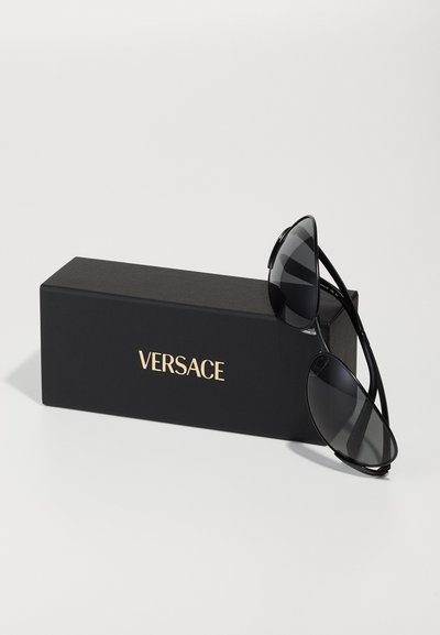 Ochelari de soare negri cu un design elegant, având lentile tonificate și rame subțiri negre, așezați lângă o cutie neagră cu logo-ul auriu "VERSACE".