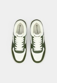 Λευκά και πράσινα χαμηλά αθλητικά παπούτσια Champion με κορδόνια, σε θέαση από ψηλά πάνω σε απλό ανοιχτό γκρι φόντο.