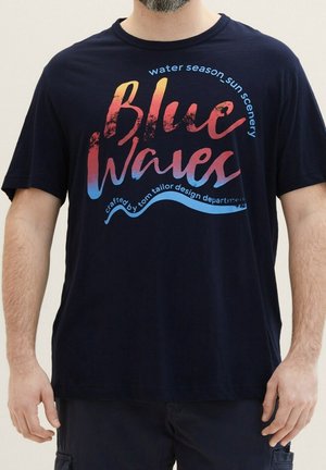 Granatowy bawełniany T-shirt z krótkim rękawem; posiada kolorowy nadruk z napisem "Blue Waves" oraz dekoracyjny tekst w różnych kolorach.