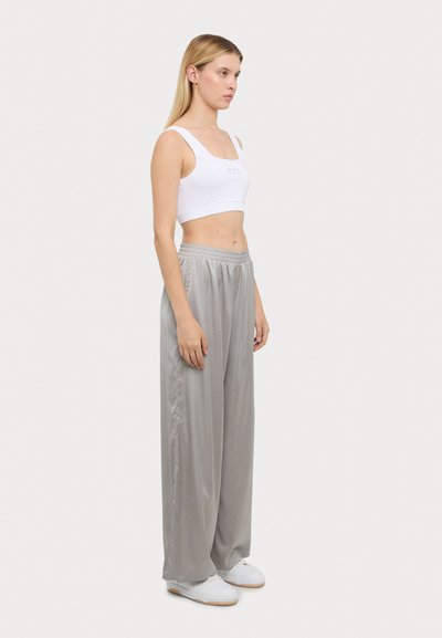 Débardeur blanc court et pantalon en satin gris ample. La tenue présente un décolleté carré et une taille élastique avec des poches latérales.