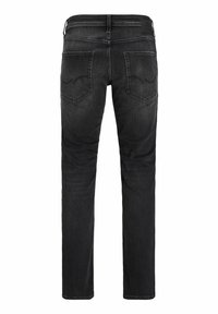 Črne ozke kavbojke prikazane od zadaj z dvema zadnjima žepoma, detajli z šivi, zankami za pas in majhno usnjeno znamkasto etiketo na pasu.