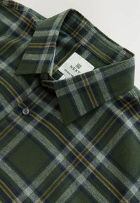 Chemise à carreaux verte et grise avec des accents jaunes, dotée d'un col boutonné et d'une étiquette en tissu indiquant "NEXT Regular Fit."