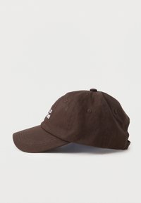 Casquette de baseball en coton brun avec une visière incurvée et un texte brodé en blanc sur le côté gauche à l'avant, présentée sur un fond clair.