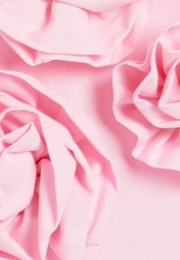 Roze stof met een zachte, gekreukte textuur die is gerangschikt in bloemachtige vormen, met zachte plooien en een gladde afwerking.