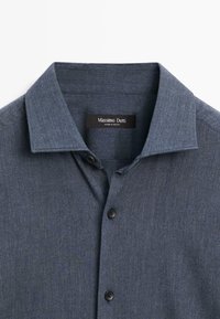 Dark blue button-up shirt with a structured collar, black buttons, and a soft, textured fabric. Brand label is visible inside the collar.