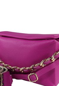 Roze leren crossbodytas met een gestructureerd oppervlak, gouden kettingaccent en een afneembare band met een opvallend patroon.