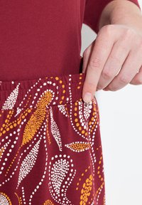 Bordeaux-coloured legginsit, millede peene riba ja kollaste punktidega. Nähtav elastne riba, sile puuvillane kangas.