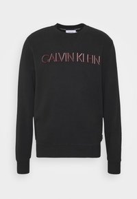 Felpa nera con collo a giro, caratterizzata da ricamo "CALVIN KLEIN" in una finitura bordeaux lucida. Tessuto morbido, polsini a costine.