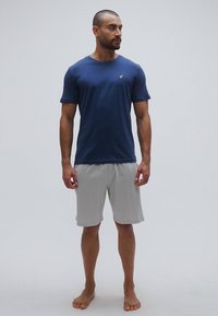 T-shirt en coton bleu marine assorti à un short gris clair, avec un design simple et une texture douce. Aucun motif ou élément métallique visible.