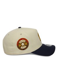 Beige Kappe mit einem marineblauen Schirm, ausgestattet mit einem gestickten runden Patch, auf dem "Yankee Stadium World Series 1938" steht. Strukturiertes Design.