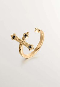 Anillo de cruz dorado con gemas negras, con una banda texturizada y extremos puntiagudos, diseñado en un estilo curvado y abierto.