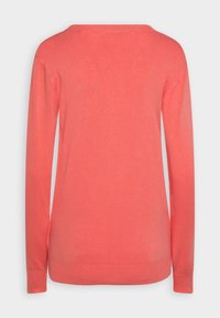 Maglione di cotone color corallo con maniche lunghe, scollo rotondo e orlo a coste, caratterizzato da una texture liscia e un design minimalista.