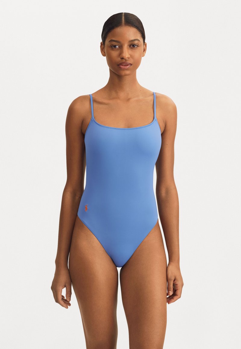 Maillot de bain une pièce bleu clair avec des fines bretelles, design sans couture, ouvertures de jambe à haute coupe et petit logo brodé sur la hanche gauche.