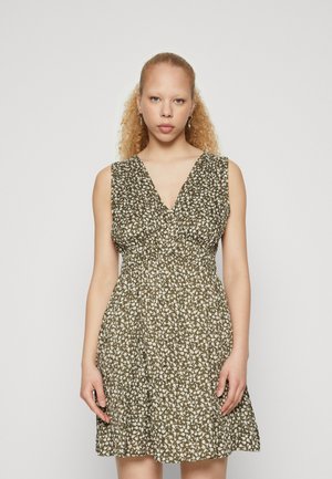 Rochie cu model floral în verde măsliniu, fără mâneci, cu decolteu în V. Dispune de un brâu elastic și o fustă evazată pentru o croială lejeră.