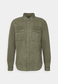 Camicia verde oliva a maniche lunghe realizzata in tessuto morbido, con chiusura a bottoni sul davanti, due tasche sul petto e un colletto classico.