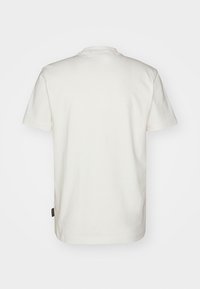 Cotton T-shirt in off-white with short sleeves, ribbed crew neck, and a small label on the lower side seam. Smooth texture.