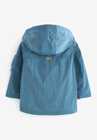 Blauwe lichte jas met een capuchon, voorzien van een klein geel label op de achterkant. Gemêleerd stof met een ontspannen pasvorm en lange mouwen.