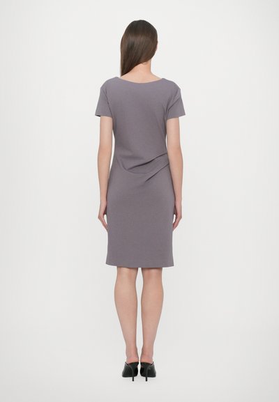 Gray knee-length dress with short sleeves, featuring a draped back detail. Made of soft, stretchy material. Black heeled shoes complete the look.