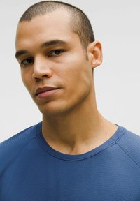 Kurzarm-T-Shirt mit Rundhalsausschnitt aus dunkelblauem Stoff mit einem strukturierten Muster. Verfügt über Raglanärmel und einen glatten Halsausschnitt.