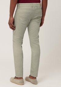 Lichtgroene slim-fit broek met een gladde textuur, vijf zakken en een leren logo patch op de achterband. Zachte stof met een op maat gemaakt ontwerp.