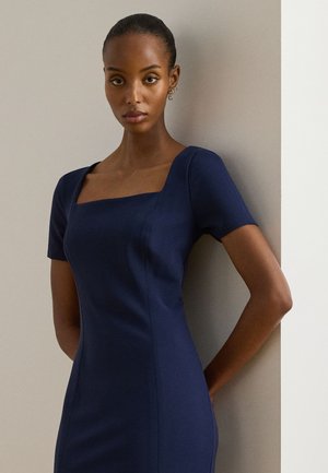 Marineblaues figurbetontes Kleid mit kurzen Ärmeln, quadratischem Ausschnitt und sichtbaren Nahtdetails, hergestellt aus einem glatten, strukturierten Stoff.