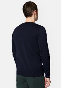 Granatowy sweter dzianinowy z prążkowanymi mankietami i dołem, z okrągłym dekoltem i gładką fakturą, pokazany z tyłu.