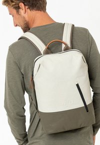 Zaino con parte superiore crema e parte inferiore verde oliva, caratterizzato da una texture liscia, dettagli in pelle e spallacci regolabili grigi.