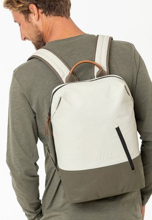 Rucksack mit einer cremefarbenen Oberseite und einem olivgrünen unteren Teil, der eine glatte Textur, Lederakzente und verstellbare graue Riemen aufweist.
