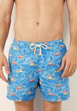 Blauwe zwembroek met een speelse print van honden op surfplanken tegen een achtergrond van golven. Tailleband met trekkoord in crème.