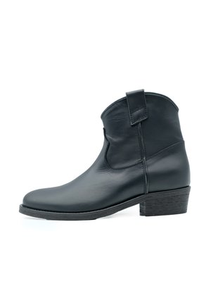 Botte de cheville en cuir noir avec un petit talon, bout arrondi et languette sur le côté. Texture lisse avec un minimum de couture pour un design épuré.