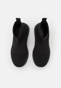 Pletené černé slip-on boty s vroubkovaným kotníkem, texturovaným svrškem a polstrovanou podrážkou. Obsahují poutko pro snadné obouvání.