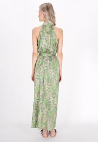 Rochie maxi cu guler halter, având un model paisley verde și roz pe un material fluid; detaliu de cusătură la talie, lungime până la gleznă.