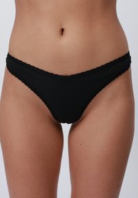 Crne rebraste bikini gaćice s dizajnom u obliku valova. Imaju nisku poziciju struka za udoban fit. Teksturirani materijal s minimalnom pokrivenošću.