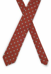 Red tie with a textured fabric featuring a repeating pattern of small white circles outlined in black. Ends are pointed.