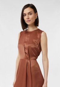 Ärmelloses, braunes Satin-Kleid mit rundem Ausschnitt, plissierten Details und glatter Textur. Verfügt über ein tailliertes Oberteil und einen fließenden Rock.